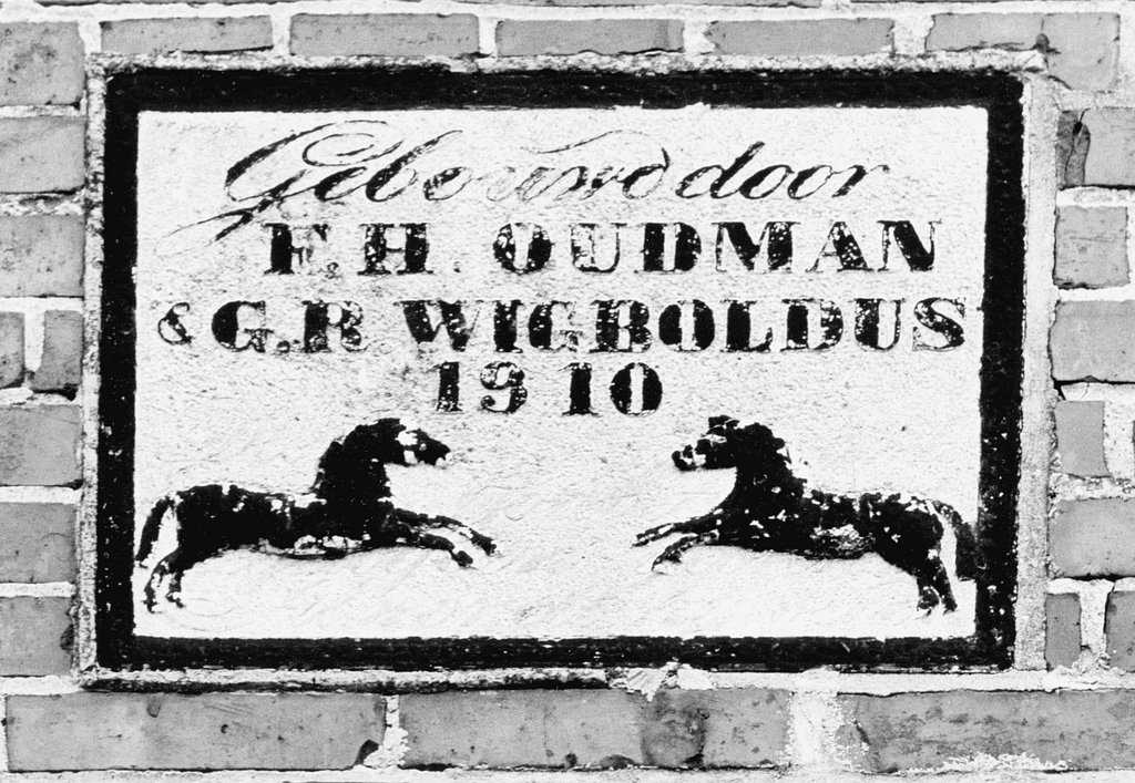 gevelsteen met een tweetal paarden en de tekst: "Gebouwd door F.H. Oudman en G.R. Wigboldus 1910"